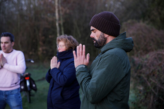 Mature woman and men with eyes closed meditating in nature