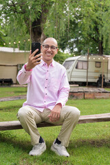 Obraz premium Full length portrait of bald Hispanic man outdoors using phone in park