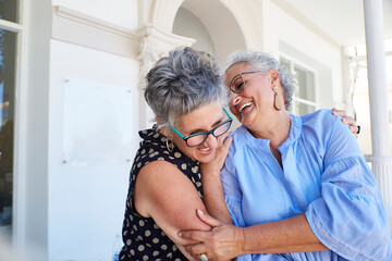 Two women laughing and hugging outdoors, enjoying retirement and friendship