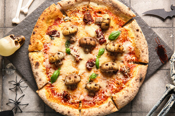 Board of tasty pizza with mushrooms, spiders, bones and skull for Halloween celebration on grey tile background
