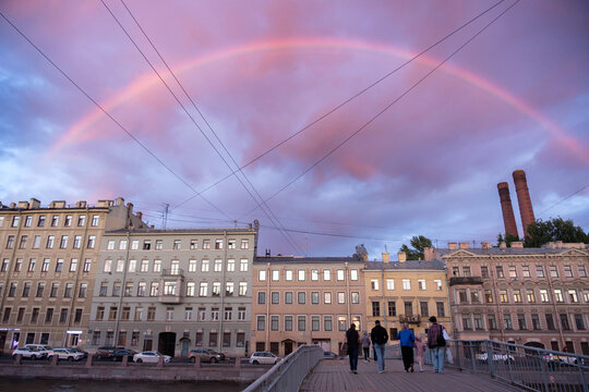 Rainbow in the sunset sky over Saint Petersburg. View of the Fontanka River embankment and Gorstkin Bridge with pedestrians