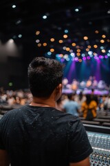 Fototapeta premium Young man overseeing sound mixing at a lively concert with colorful stage lights and an engaged audience in a modern venue setting