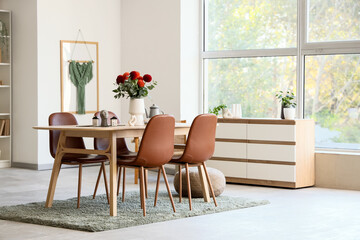 Dining table with dahlia flowers in vase in room