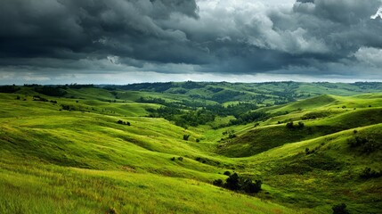 Obraz premium Vast rolling green hills under dramatic stormy skies create a breathtaking natural landscape view