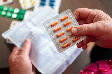 Pensioner reads medication instructions carefully. Elderly woman studies a drug leaflet, trying to understand treatment without professional help