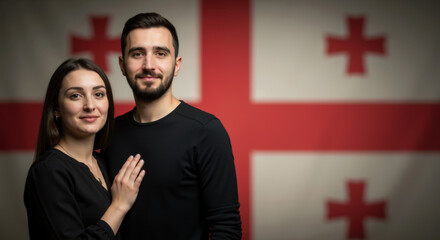 Young Caucasian couple posing together in front of Georgian flag. Studio shot of Georgian man and woman dressed in black against national Georgia flag backdrop. Independence Day of Georgia