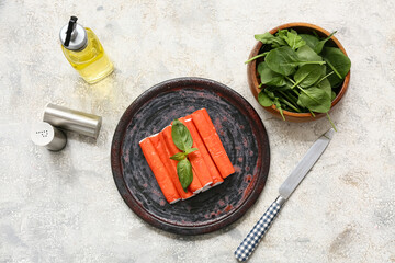Plate with tasty crab sticks, basil and spinach leaves on white background © Pixel-Shot