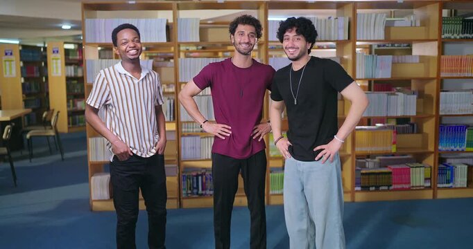 Indian asian happy young adult gen z student male man guys group standing indoor library look cam smiling boys great unity team do candid pose talk enjoy fun joy joyful day break time