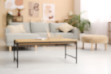 Comfortable sofa, pouf and coffee table in interior of living room. Blurred view