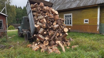 Truck unloading firewood in front of wooden house in countryside