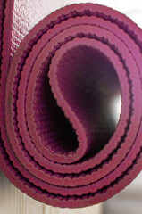 Obraz premium vertical shot of a rolled-up magenta yoga or exercise mat, highlighting its texture and color..