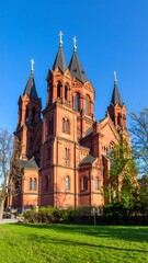 Fototapeta premium Brick church, three towers, clear sky, green lawn