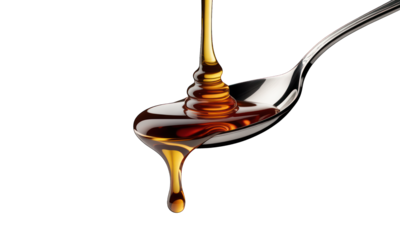 Dripping syrup forms liquid layers on a silver spoon, black backdrop