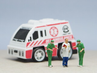 Mini toy of action figure at table with blurred background. Miniature photography concept design. Minifigure of paramedic crew character with ambulance. Rescuing patient. © awstoys