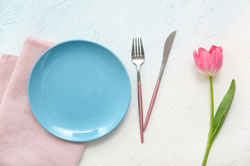 Beautiful table setting with pink tulip flower on light blue background