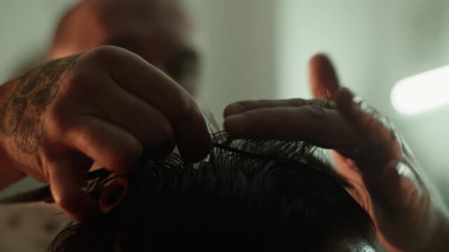Barber trims client hair with scissors and comb for precise cut