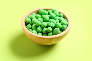 Bowl with wasabi coated peanuts on green background