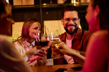 Group of Friends Enjoying Drinks and Smiling During a Casual Evening Gathering