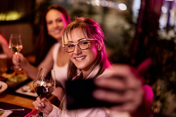 Young Woman Enjoying a Celebration, Taking Selfie With Friends at Restaurant