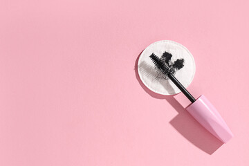 Composition with dirty cotton pad and mascara on pink background, closeup
