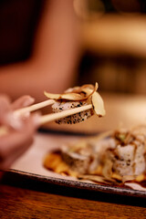 Close-Up of Elegant Sushi Being Held With Chopsticks at a Restaurant