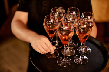 Server Holding Tray With Sparkling Rosé Wine Glasses in Elegant Setting