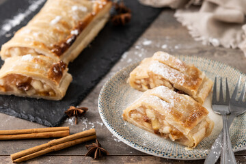 Homemade apple strudel slices in plate on wooden table. Traditional Austrian and German sweet