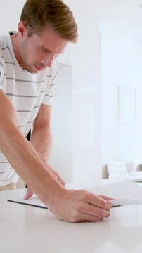 Vertical video: Couple scanning contract on kitchen island, sipping mug then signing documents