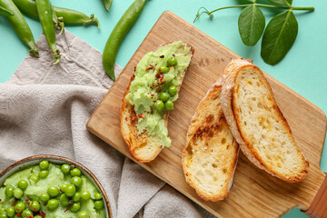 Bowl with mashed green peas and bread slices on turquoise background