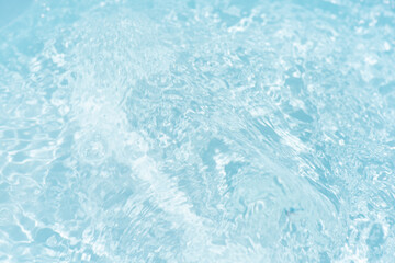 Blue water with ripples on the surface. Defocus blurred transparent blue colored clear calm water surface texture with splashes and bubbles. Water waves with shining pattern texture background.