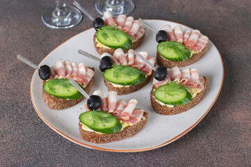 Sandwiches with bacon, cucumber and black olives on toast from rye bread