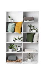 Shelf unit with green plants and pillows on white background