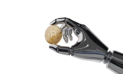 Robot hand holding a golden coin, isolated on black, in a futuristic design