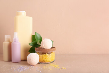 Bath bombs with plant, sea salt and bottles of cosmetic products on beige table