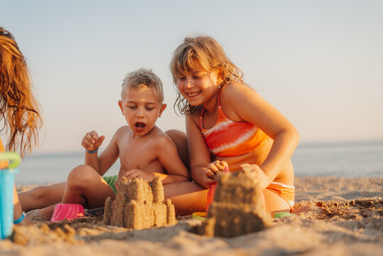 Children building sandcastles on beach at sunset