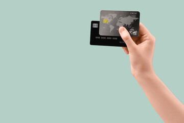 Female hand with credit cards on light turquoise background