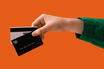 Female hand with credit cards on orange background, closeup