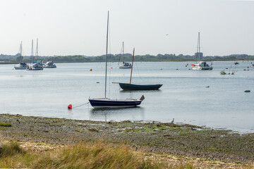 Mudeford Sandbank, Southbourne, UK - August 10th 2025: Two sailboats moored in Christchurch Harbour near the beach.