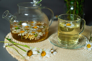 Herbal tea with chamomile flowers in glass teapot and cup. Herbal tea brings relaxation, herbal tea...
