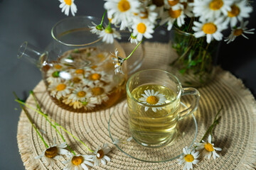 Eco product chamomile tea poured into glass cup from teapot. Eco product reflects sustainability,...