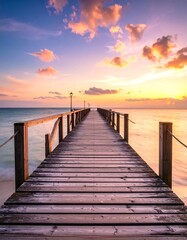 Naklejka premium Wooden pier at sunset over calm ocean