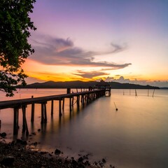 Obraz premium Wooden pier at sunset over calm water (1)