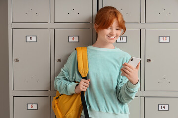 Teenage schoolgirl using mobile phone near locker