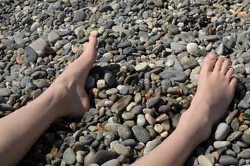 child's feet on a pebble beach by the sea