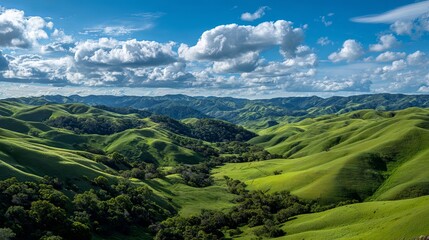 Obraz premium Stunning verdant rolling hills under a bright blue sky with dramatic clouds, showcasing nature's beauty.
