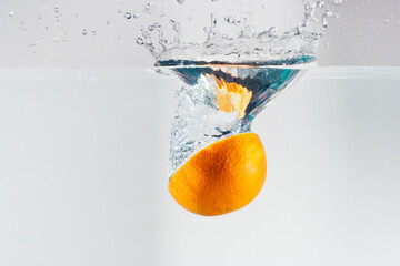 Vitamin C, orange piece dropped into water