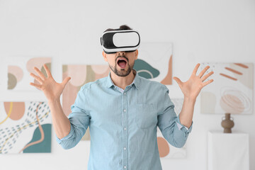 Shocked young man with VR glasses in modern art gallery