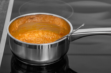 There is a pot on the stove with a rice dinner dish ready to be heated up.