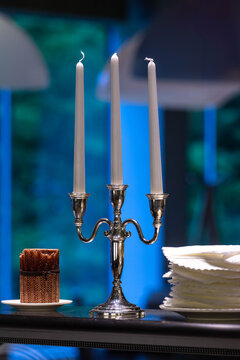 A close-up of an elegant silver candelabra with three lit white candles. The image evokes a sense of romance, celebration, and refined dining atmosphere.