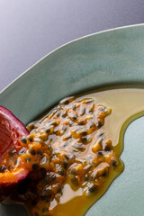 Fruit and juice spilling out of a halved passion fruit on a plate
